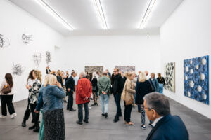 Personen im Saal betrachten die ausgestellten Kunstwerke