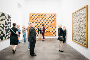Personen im Saal betrachten die ausgestellten Kunstwerke