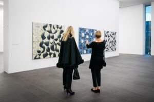 Zwei Frauen betrachten Kunstwerke an der Wand